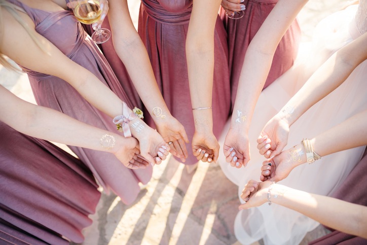 Hands of bridesmaids and bride with drawings on the wrists