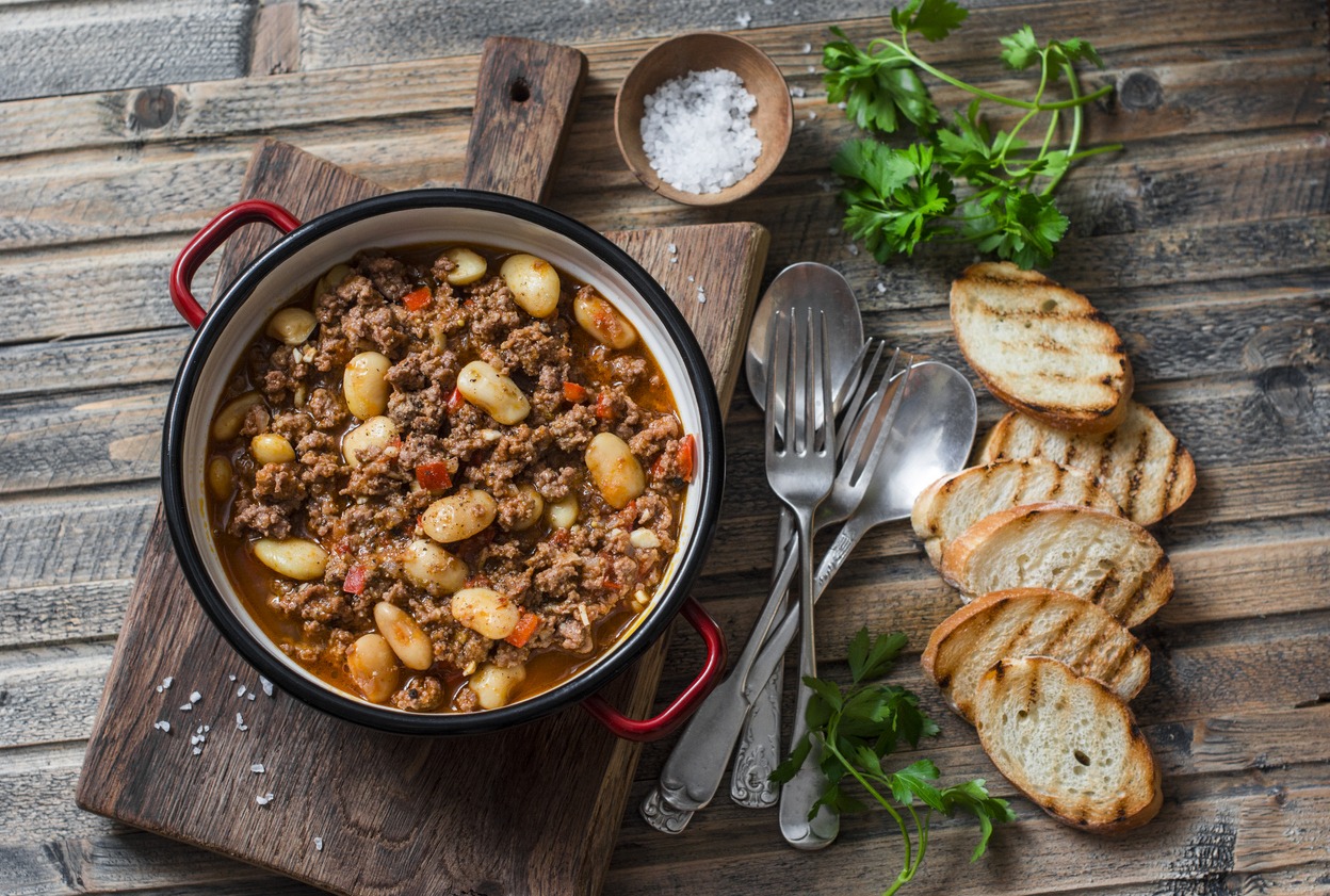 Cannellini beans beef slower cooker stew on the wooden table top view autumn winter