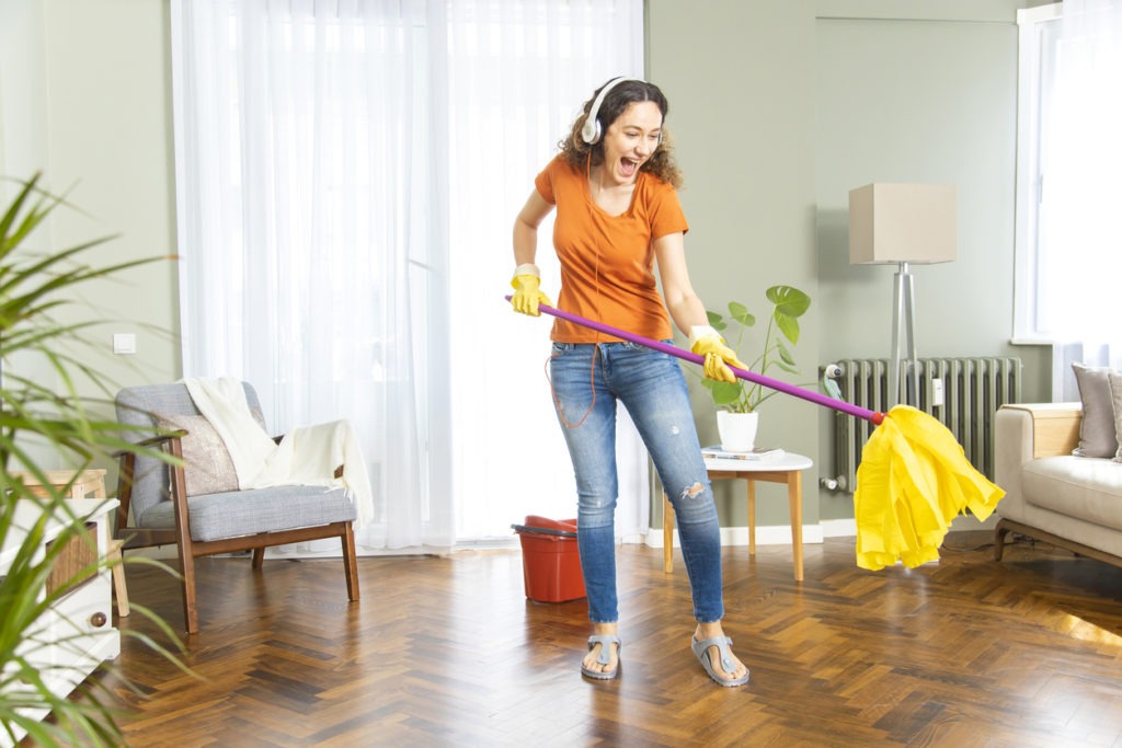 Cheerful woman cleaning the house with a flat mop