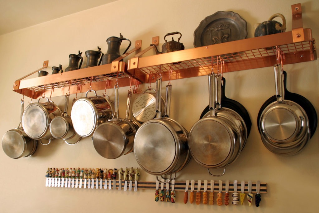 Close-up of metal pots and pans hanging on the kitchen wall
