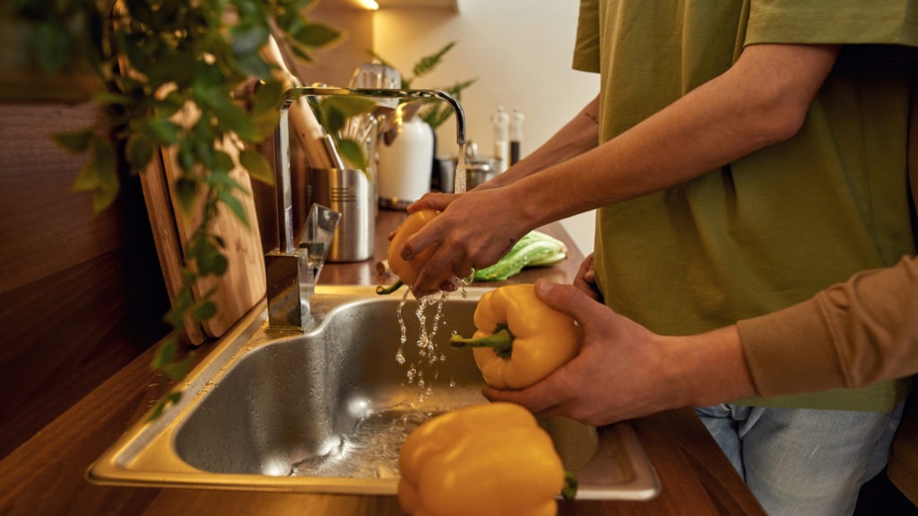 Couple washing fruits and vegetables before peeling
