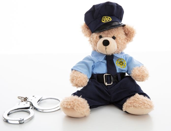 Cute teddy in policeman uniform and handcuffs