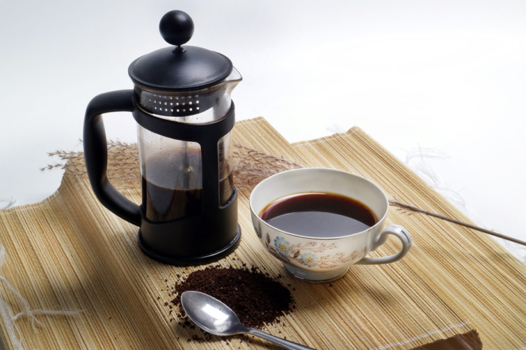 French press coffee with cup of coffee and coarse coffee powder
