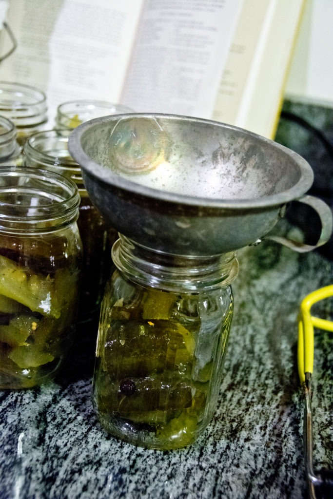 Large canning funnel on pickle jar with other pickle jars in the background