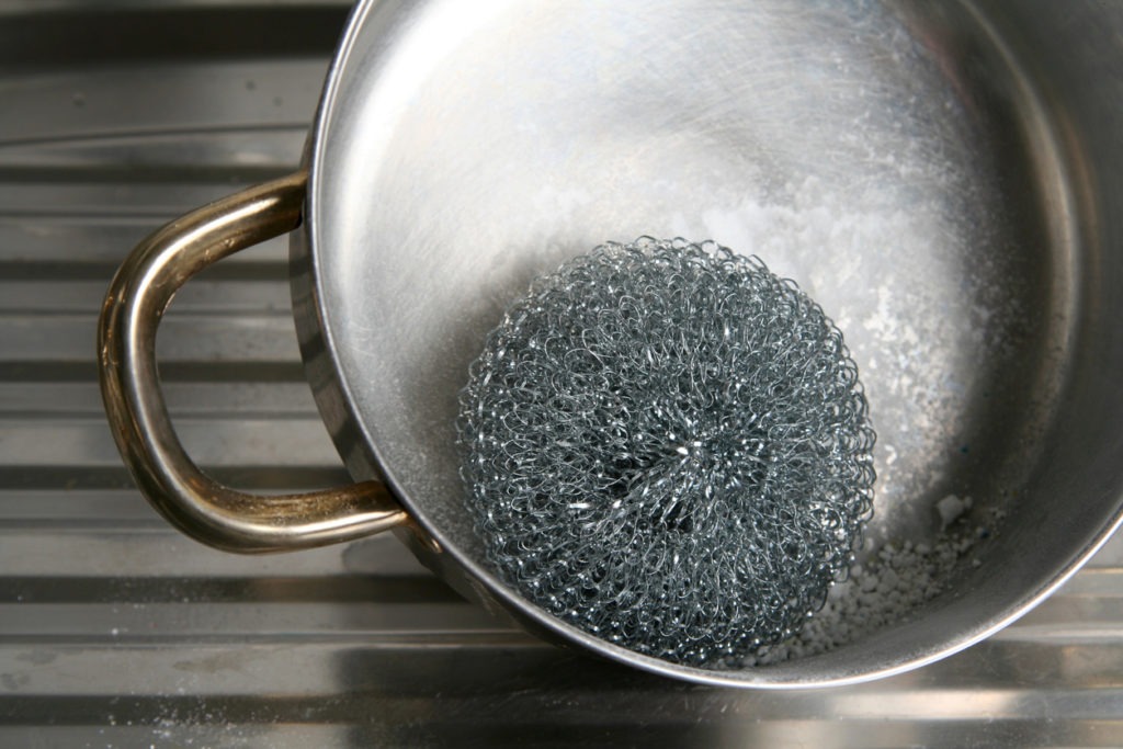Metal pot cleaning with wire wool and powder