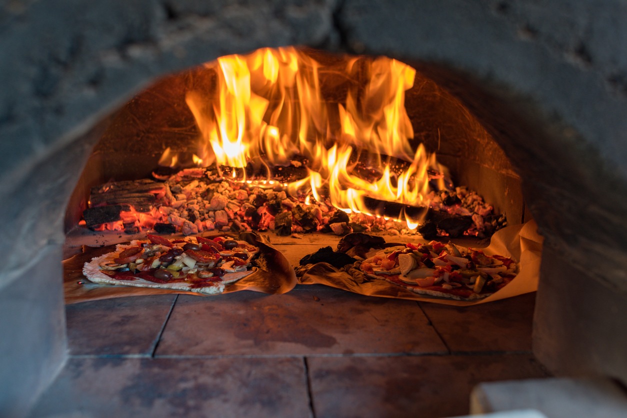 Pizza oven with flame, with blazing fire from wood and charcoal and two pizzas inside