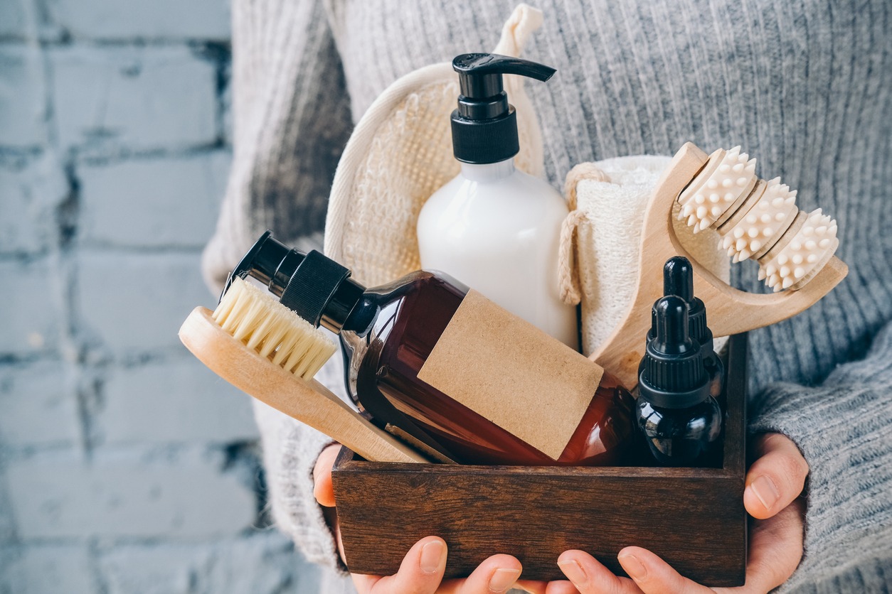 Spa facial and body skin care products. Lotion, essential oil, cream, massage brushes and anti-cellulite in a basket in the hands of a young woman