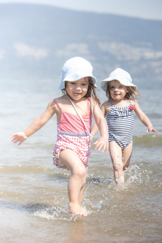 Two little girls wearing a sun hat on the beach