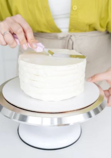 View of a woman layering the cake with a spatula on her hand 