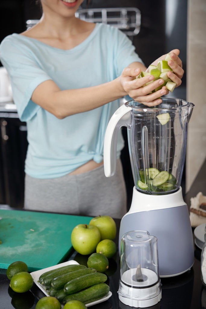 Woman placing fruit slices into a blender