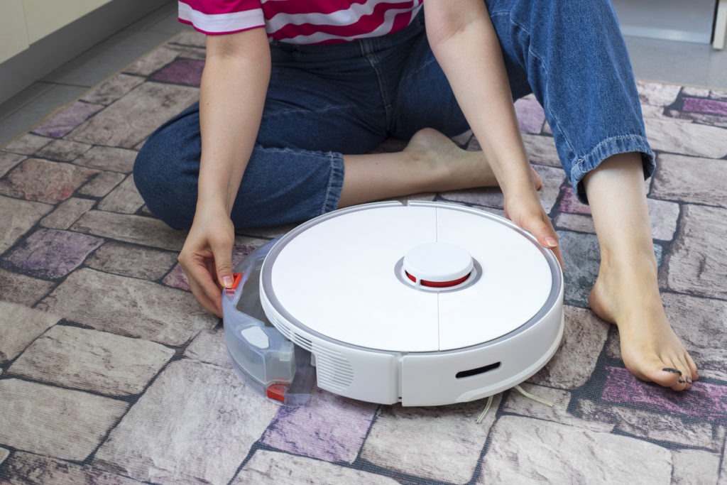 Young woman putting a mop on a robotic vacuum cleaner
