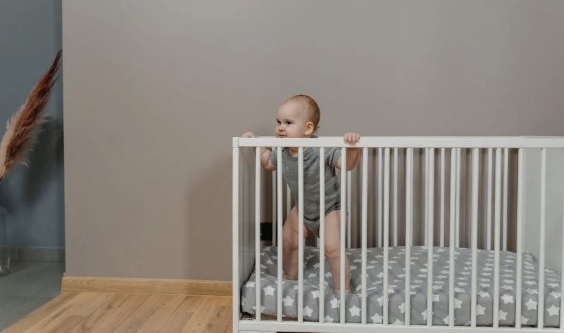 a baby standing inside a white crib