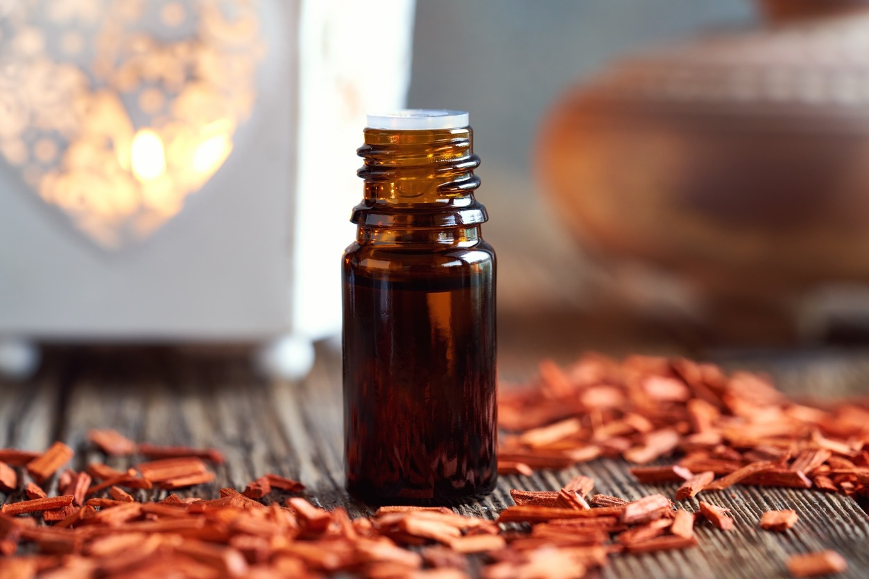 a bottle of aromatherapy essential oil with pieces of red sandalwood