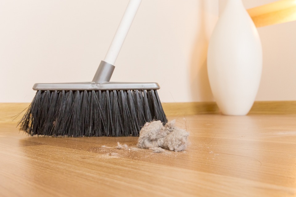 a polypropylene broom and a clump of dirt on the floor