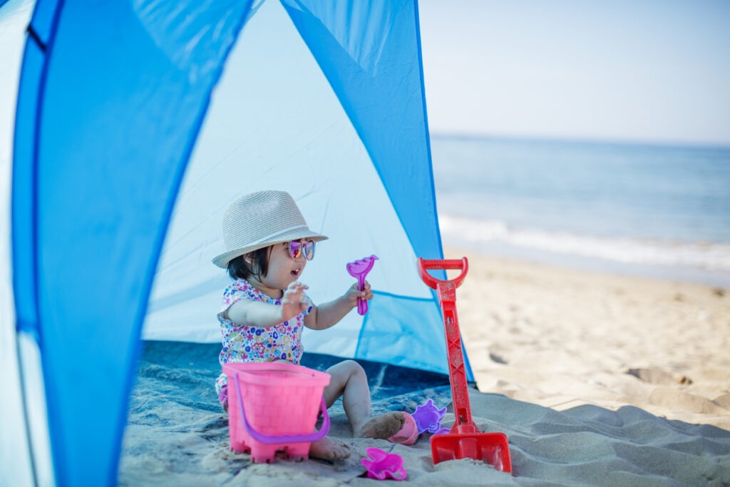 baby girl in a tent at the beach