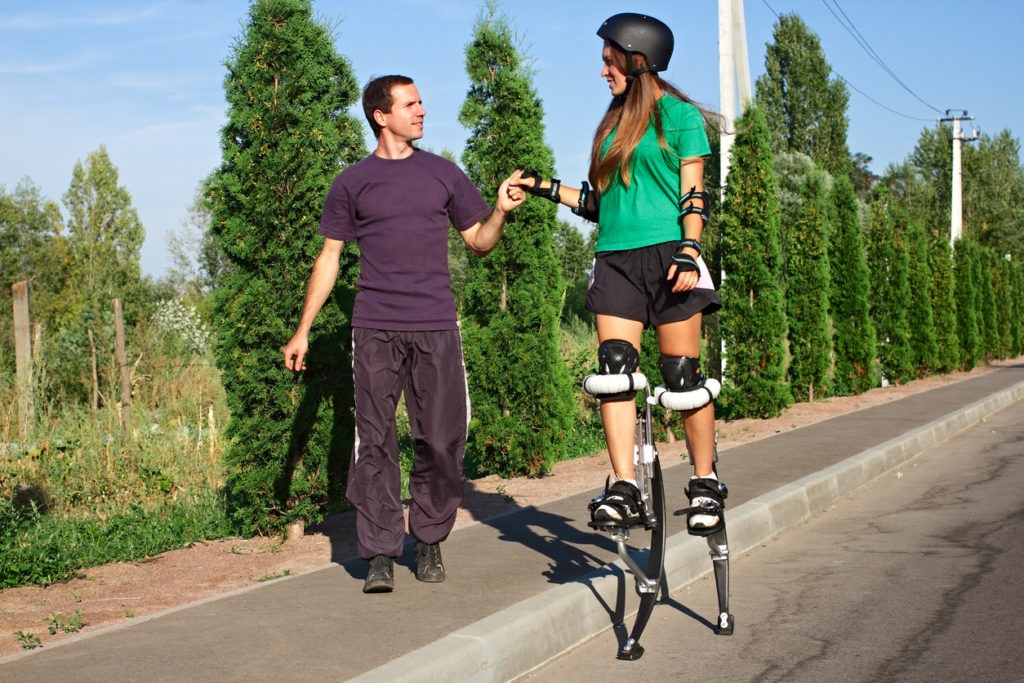 Boy helps the girl to walk on stilts