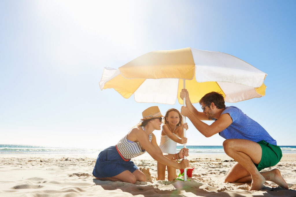 family setting up a beach umbrella