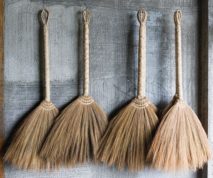 four Filipino soft brooms hanging on a cemented wall