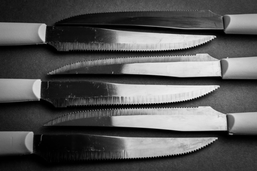 kitchen knife blades on dark gray background, black and white image, abstract background