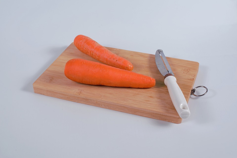 peeled carrots and a peeler on a chopping board