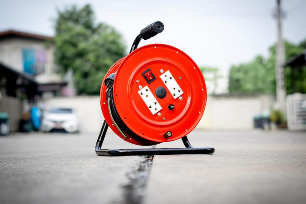 Red extension cord reel with 4 sockets and on-off switch on the floor.