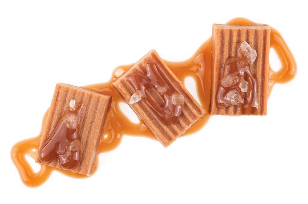 Salted caramel pieces isolated on a white background, top view. Caramel candies with liquid sauce.