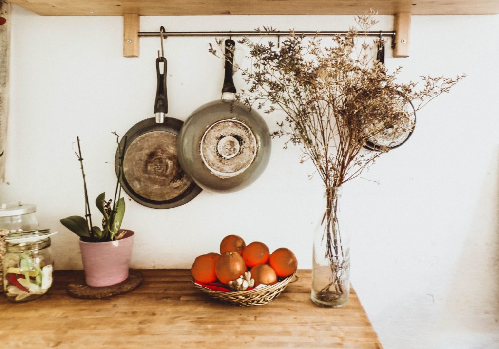 two gray frying pans hanging on wall scaled