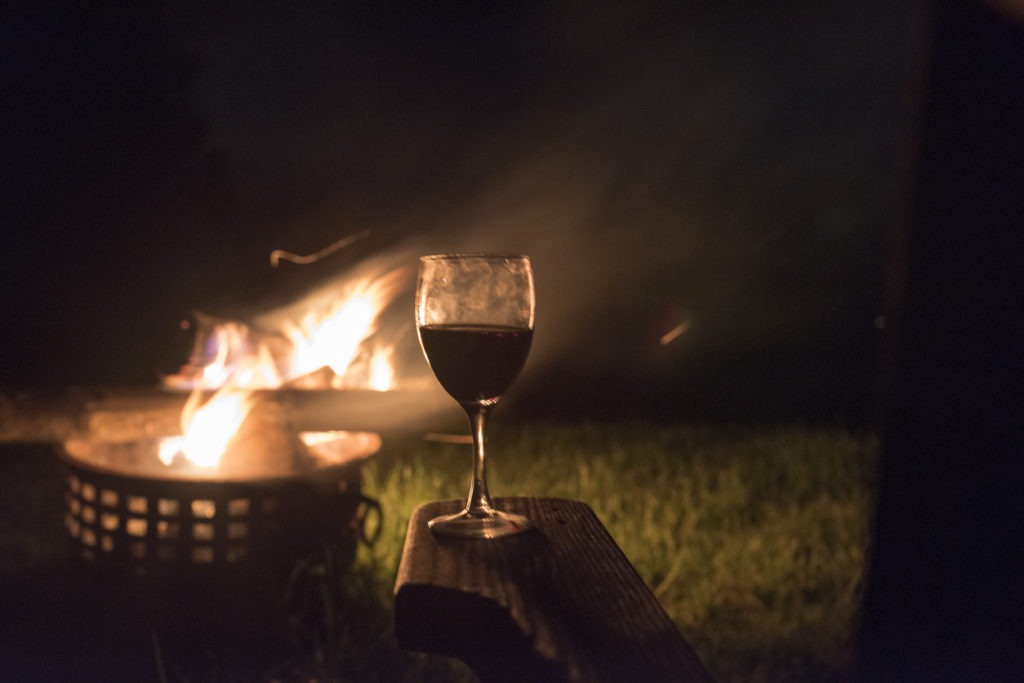 woman enjoys a glass of wine while looking at an outside fire