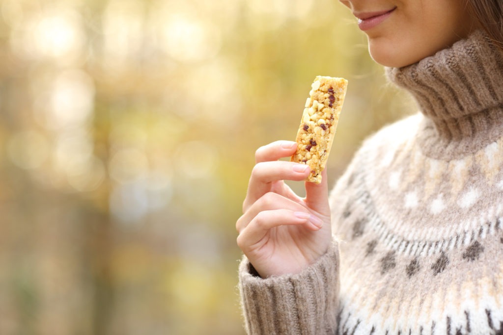 Woman holding a cereal bar ready to eat in autumn