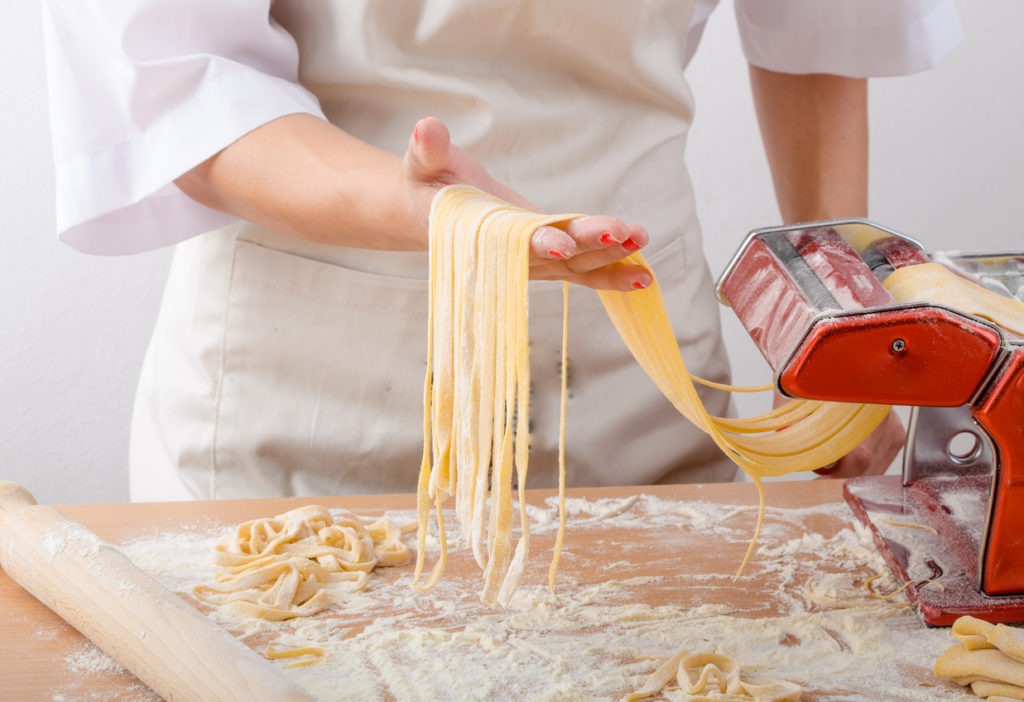 Young woman chef prepares homemade pasta