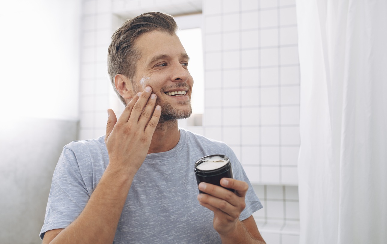 A man applies aftershave lotion to his beard