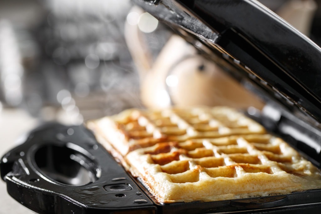 Freshly baked traditional Belgian waffles in an iron waffle maker. family morning, prepare Breakfast