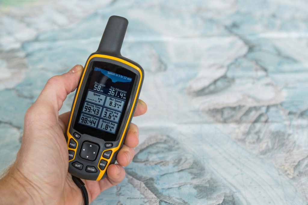  Hand-held outdoor GPS and a hiking map of a mountain range