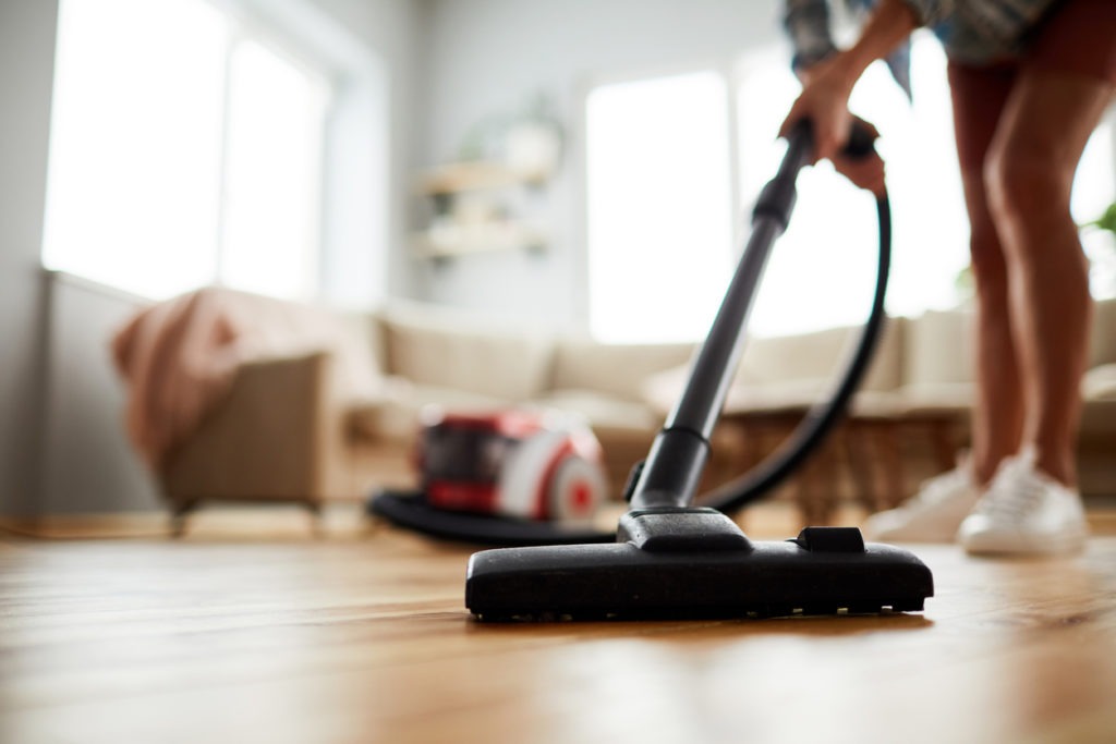 Vacuuming a hardwood floor in a house.