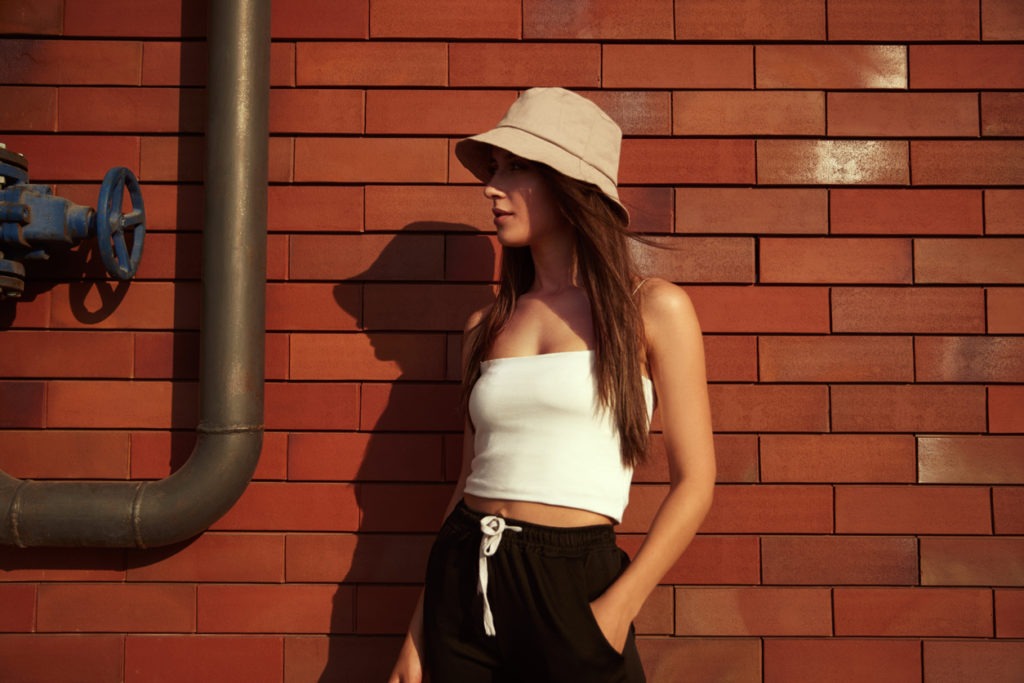 Woman standing near brick wall wearing a trendy bucket hat