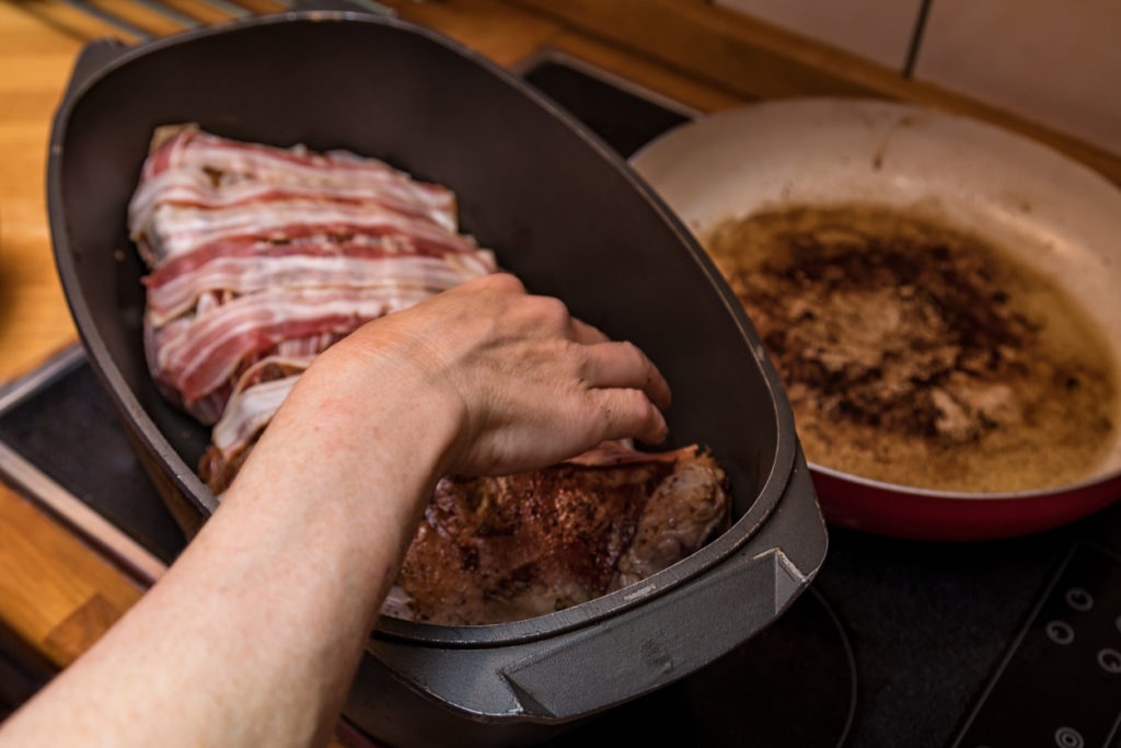 Woman’s hand filling a pan with bacon 
