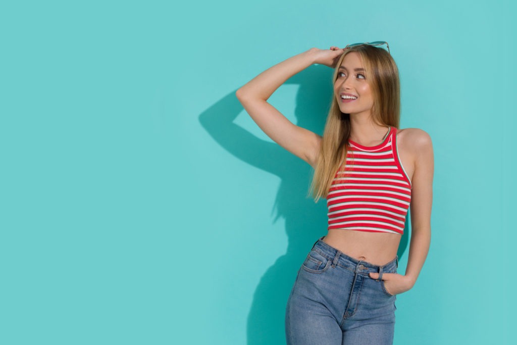 Young Woman in Striped Crop Top is Looking Away and Smiling.