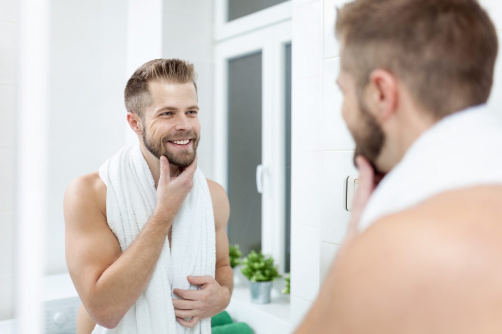 a bearded man smiling at himself in the mirror 