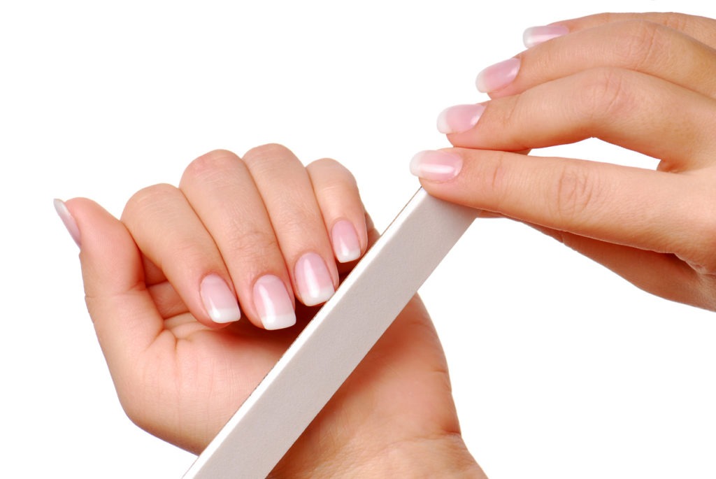 a close-up image of a woman’s hand using a nail file