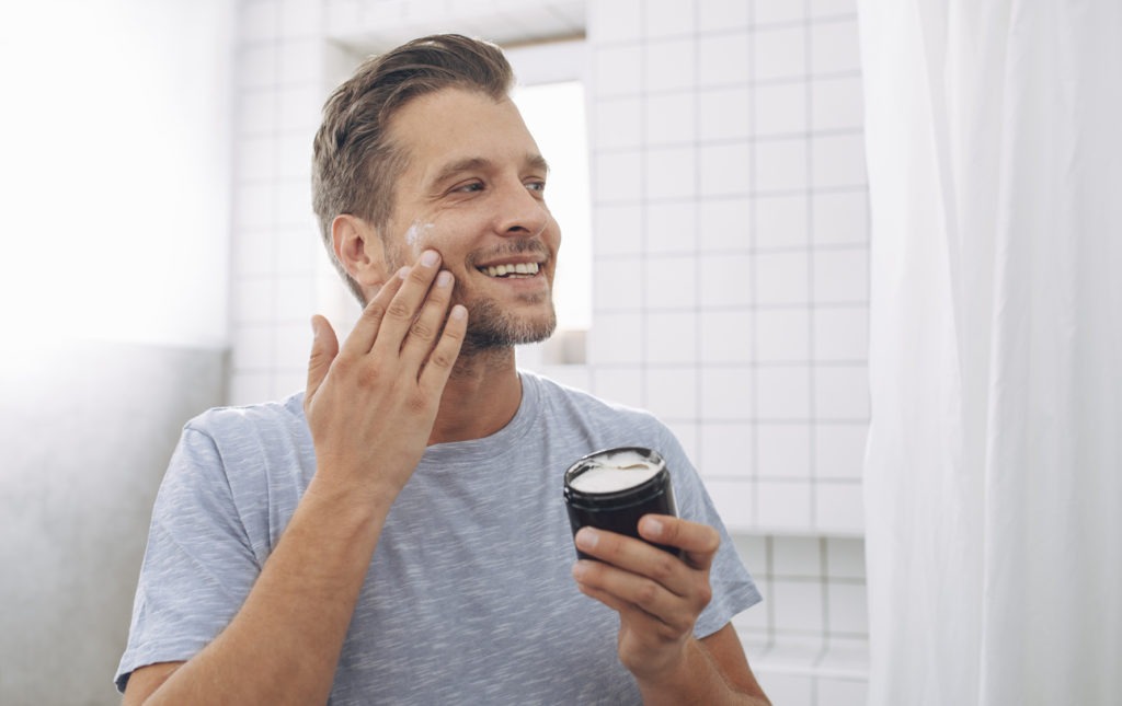  a man applying moisturizer on his beard