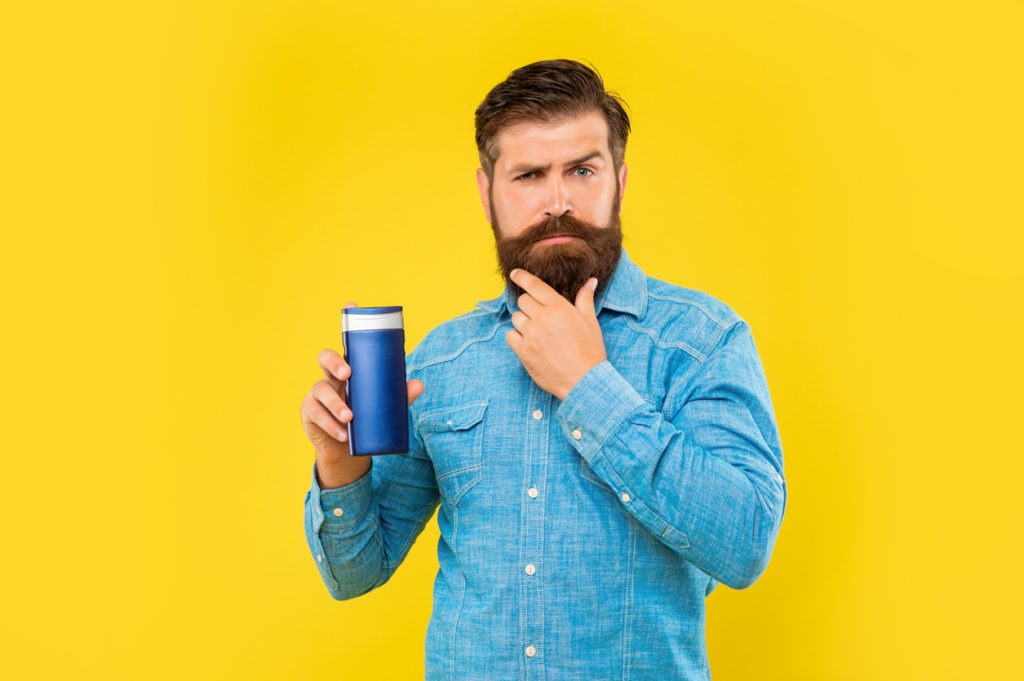 a man holding a bottle of beard conditioner
