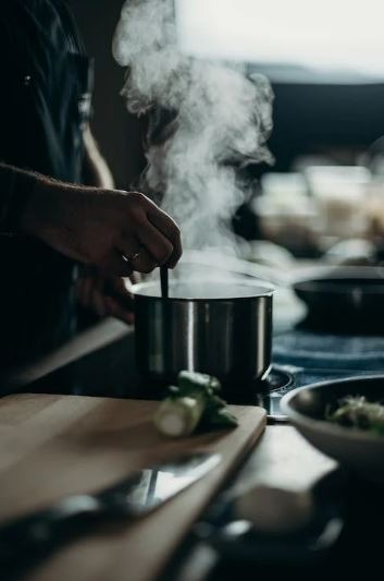 a person cooking in a pot inside the kitchen