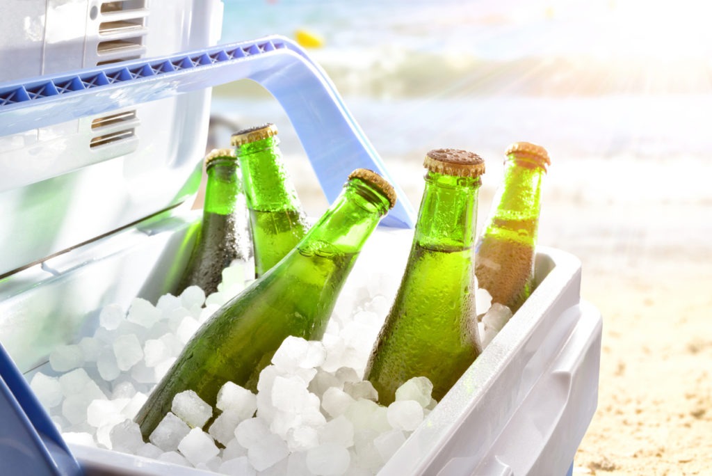 Beer chilled on ice in camping fridge on the beach