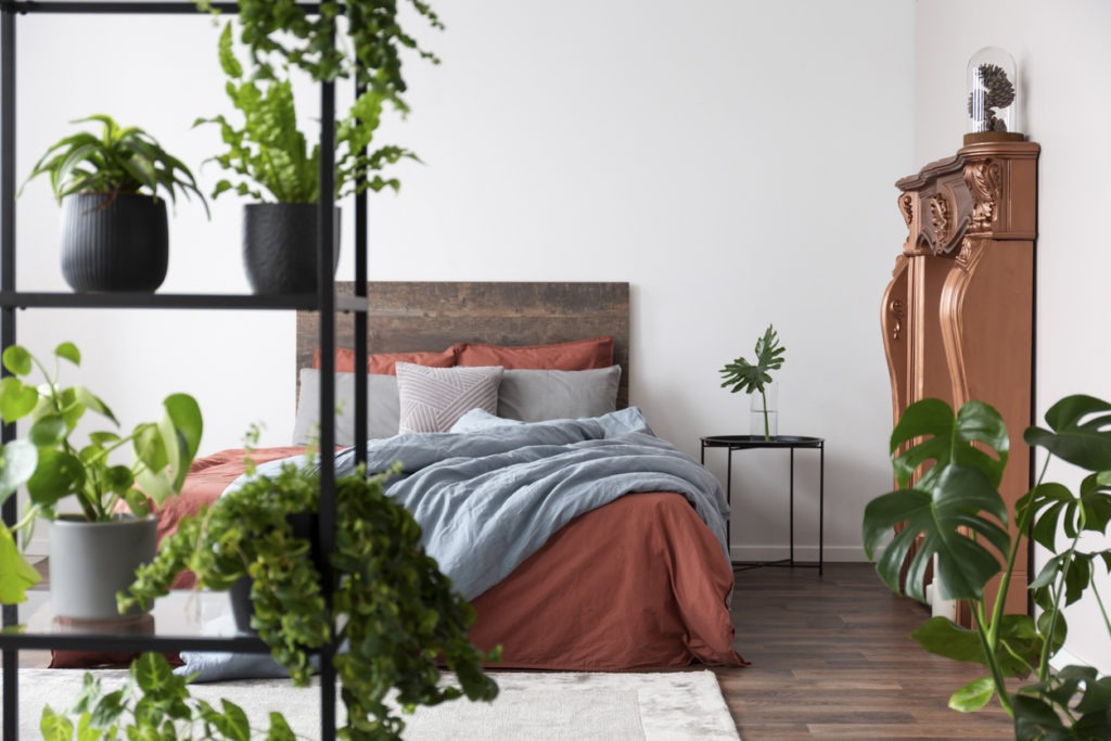 Bright modern bedroom full of plants and with coppery decor