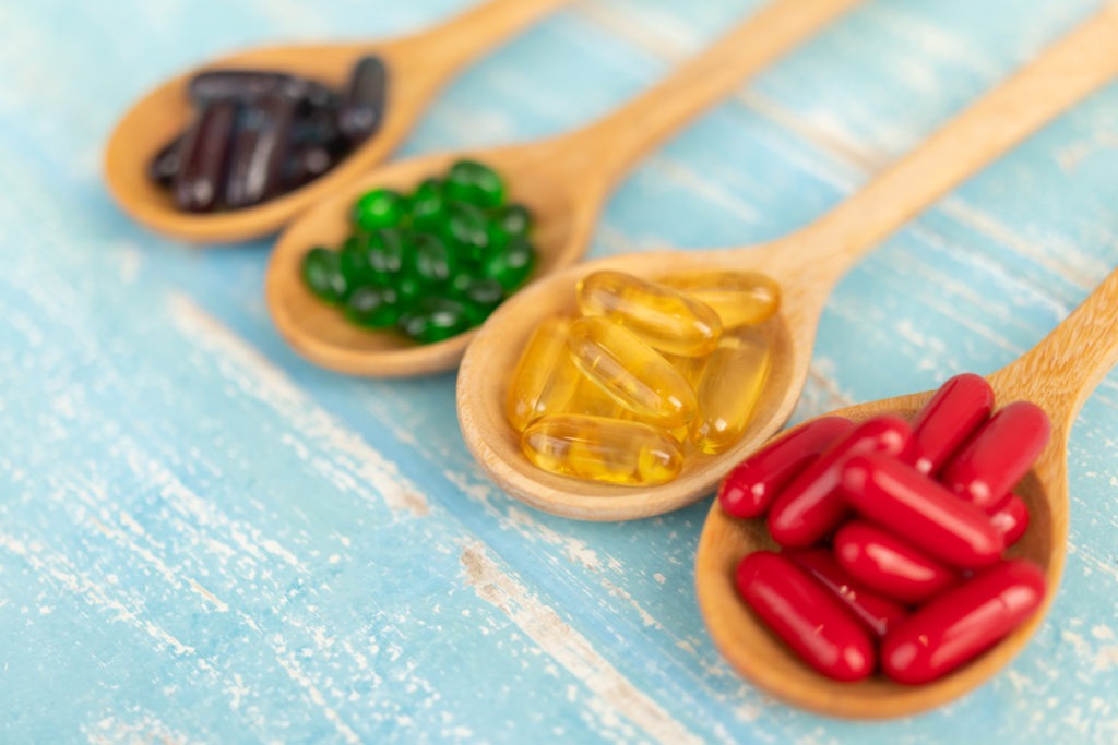 different soft gel capsules in wooden spoons