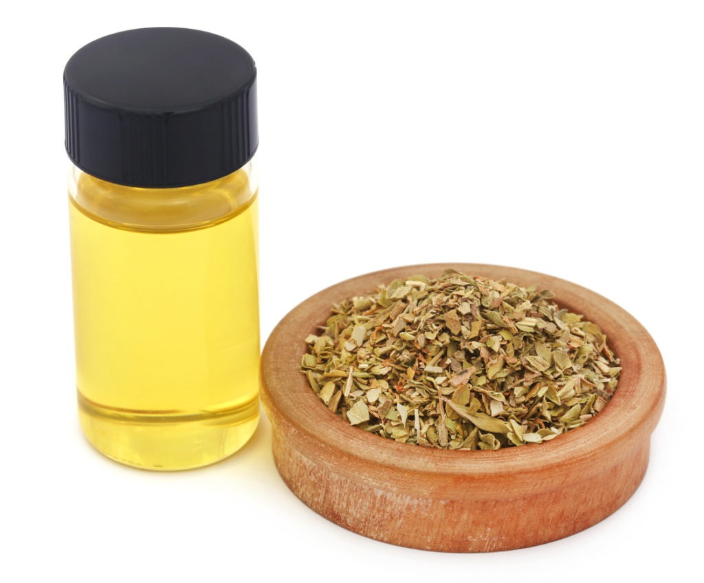 dry oregano and essential oil in white background