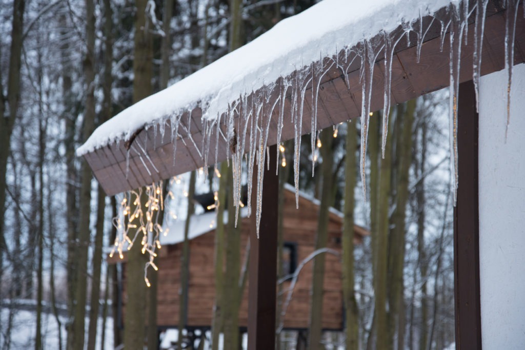 Icicles hang from the roof. Christmas garlands are visible in the background