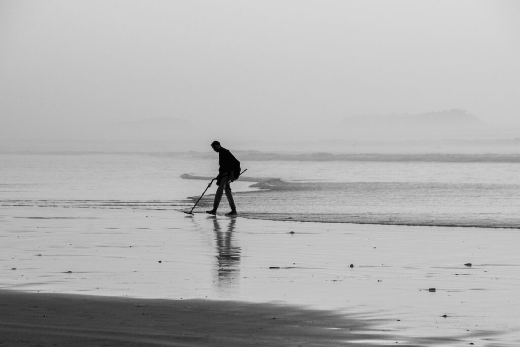 man using a metal detector on the beach