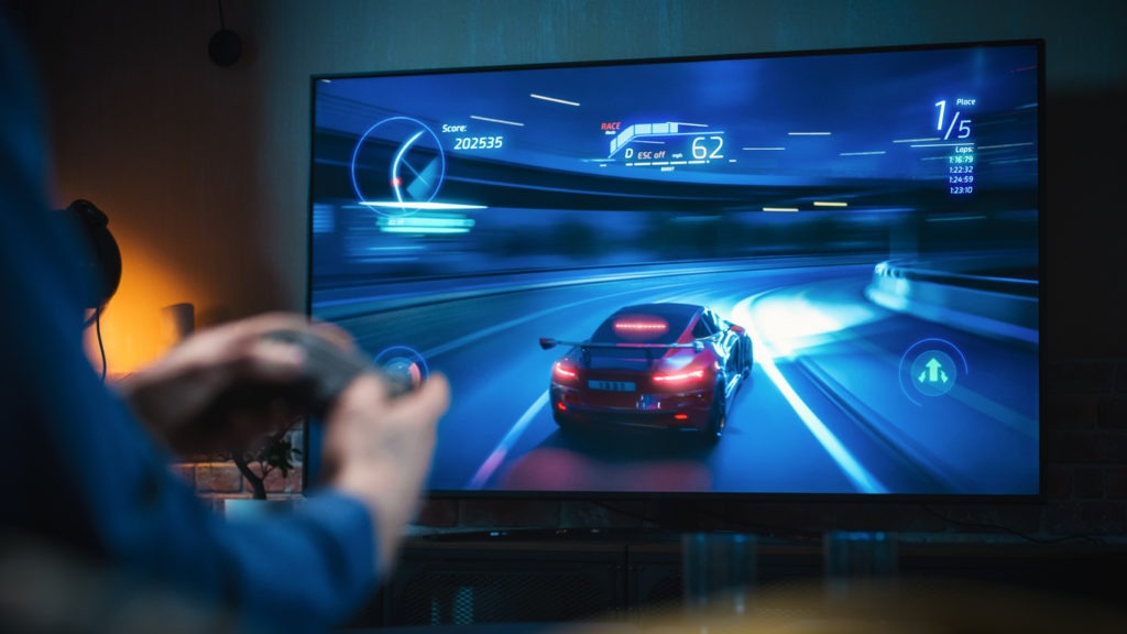 Man's Hands at Home, Sitting on a Couch in Stylish Loft Apartment and Playing Arcade Car Video Games on Console. Male Using Controller to Play Street Racing Drift Simulator