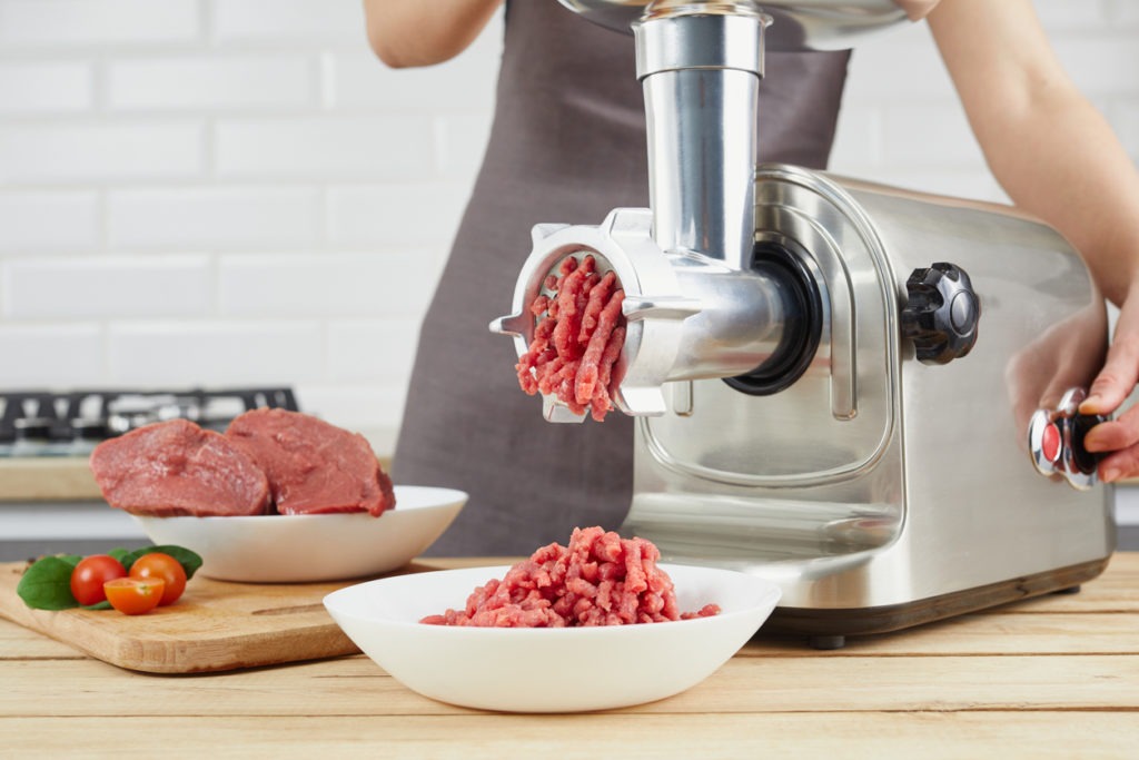 Woman grinding meat using an electric meat grinder